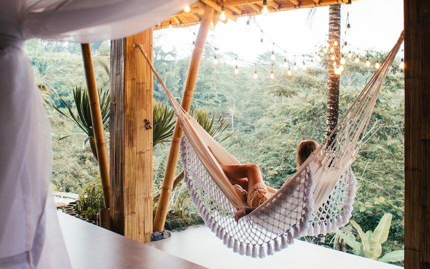 unrecognizable traveler in hammock against bed in tropical resort